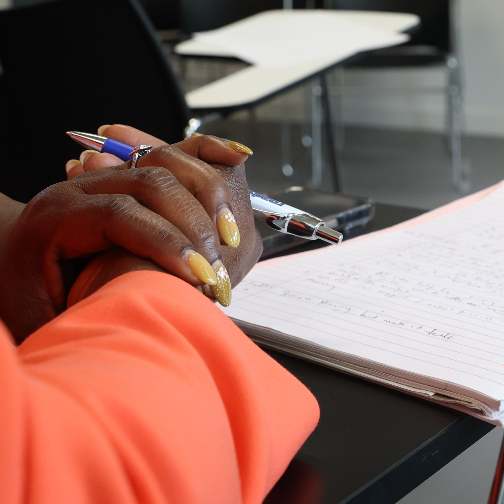 Hands holding a pen in front of a notepad